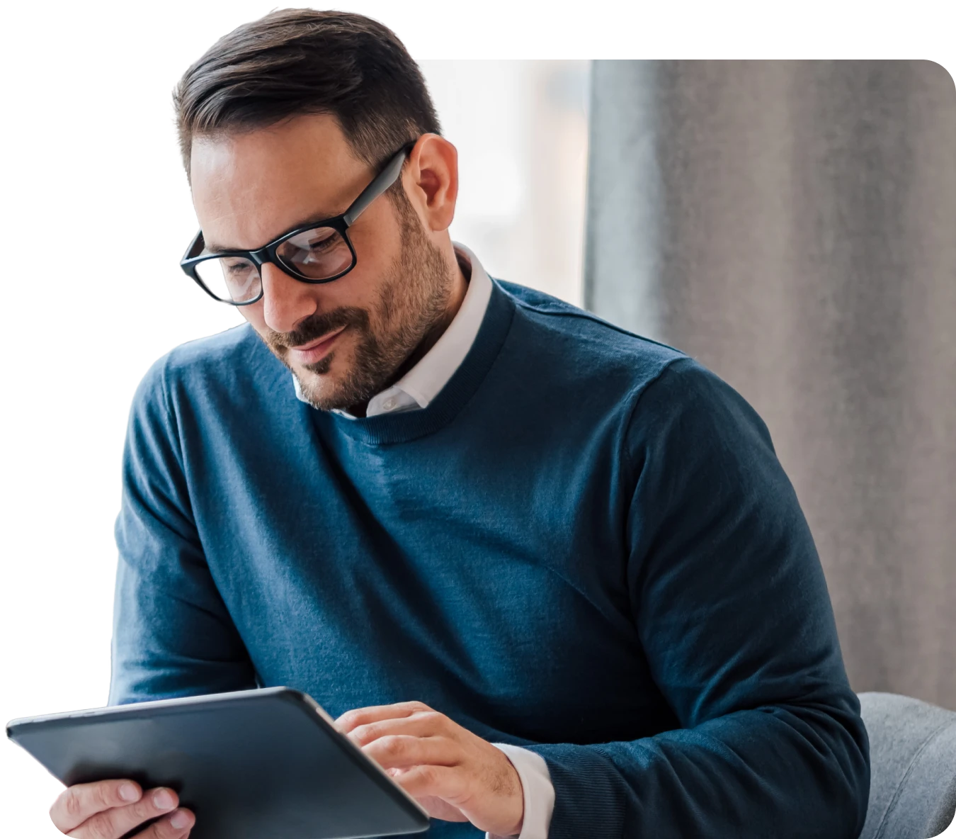 Mann mit Brille im blauen Pullover arbeitet an einem Tablet